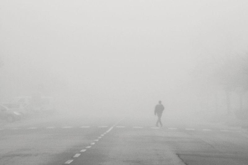 Rear view of man walking on road in foggy weather