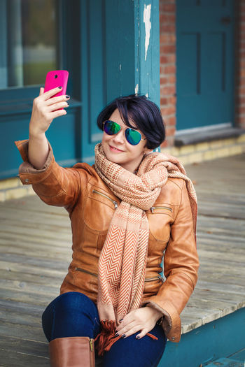 Woman wearing sunglasses taking selfie with smart phone