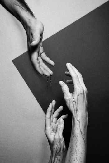 Cropped image of hands reaching towards each other against wall