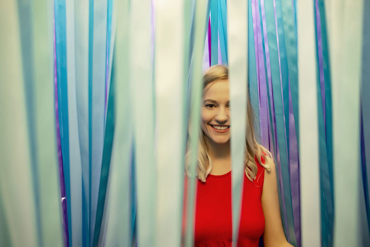 Smiling young woman standing against curtain