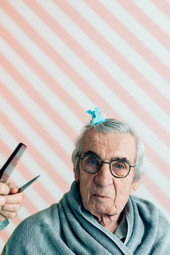 Elderly man with a hairpin looking at the camera ready for the haircut at home or in a barbershop