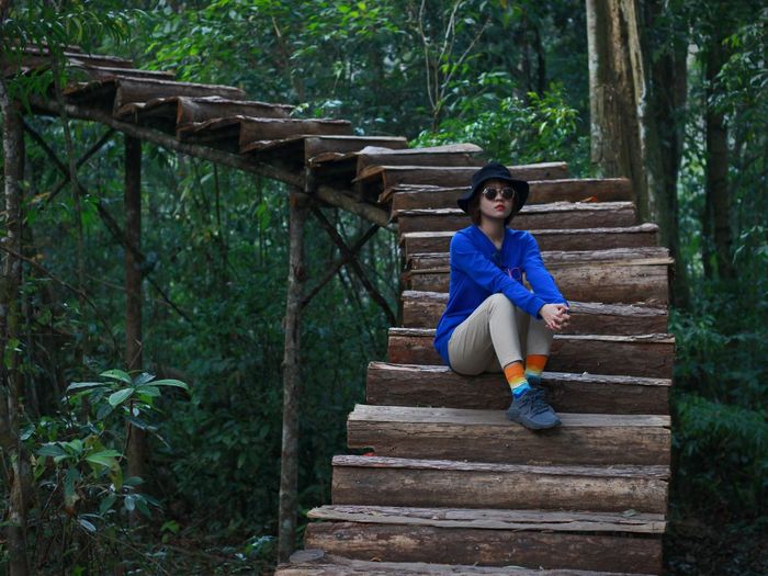 Full length of woman sitting on wooden footbridge