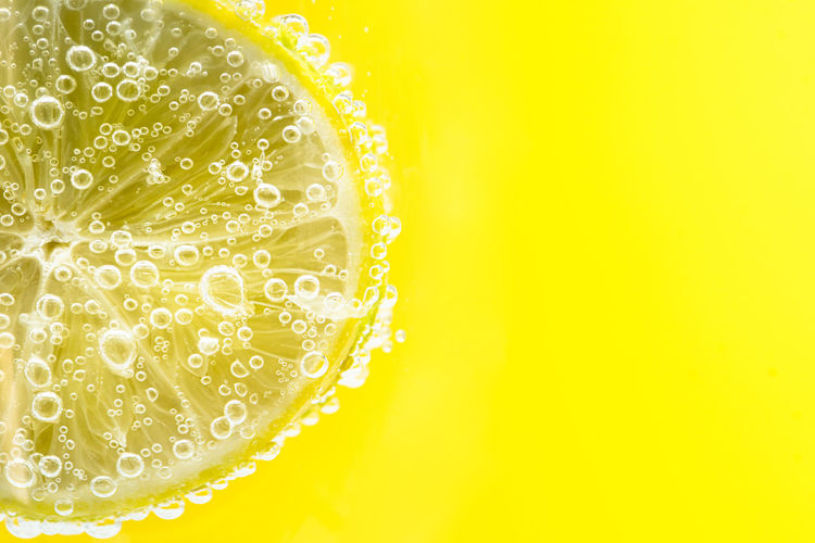 Close-up of water drops on glass against yellow background