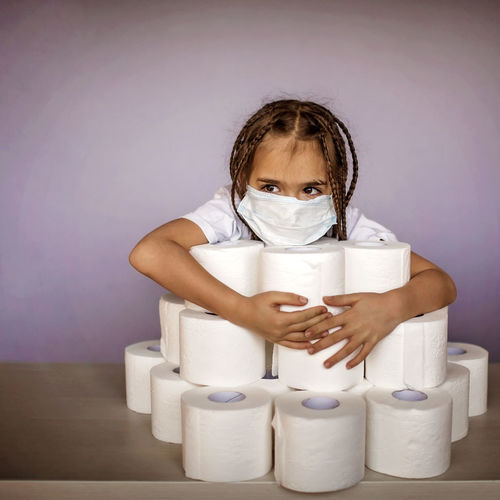 Close-up of girl wearing mask with toilet paper on table