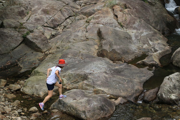 High angle view of woman walking on rock by stream