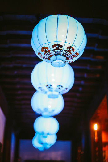 Low angle view of illuminated electric lamp hanging on ceiling