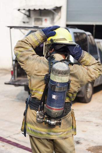 Firefighters put on firefighting suits with air tanks.