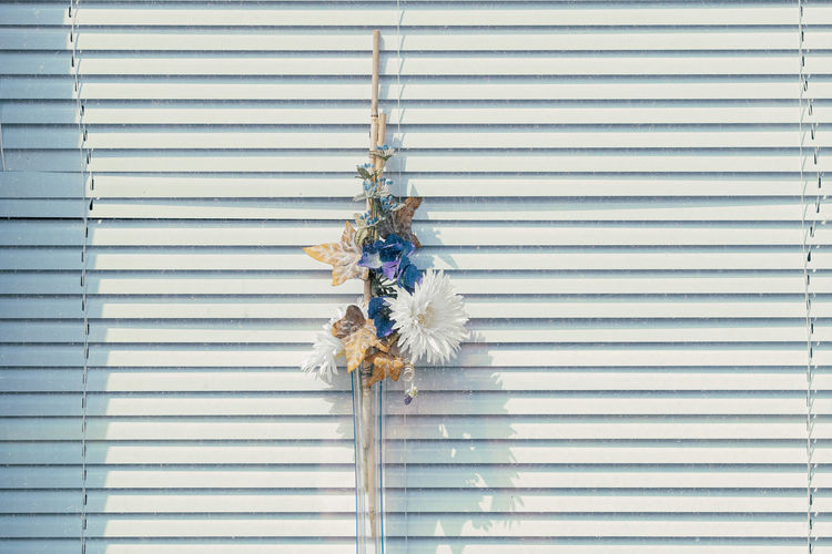 Plastic flowers in front of window blinds