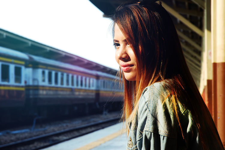 Side view of young woman looking away on railroad platform