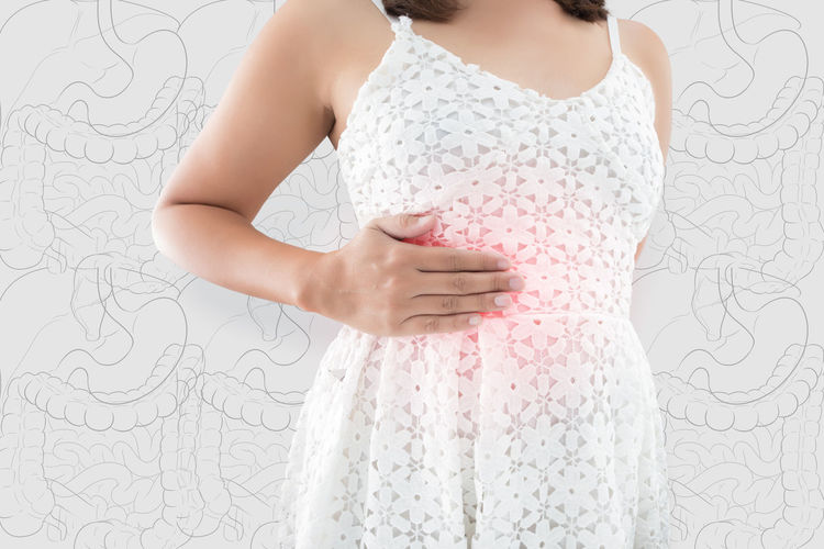 Digital composite image of woman with stomachache standing against wall