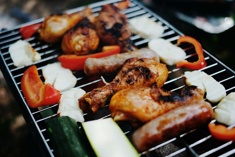 Close-up of chicken wings and vegetables on barbecue grill