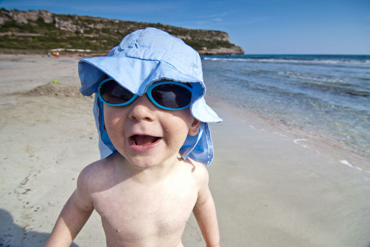 Portrait of shirtless boy wearing sunglasses at beach