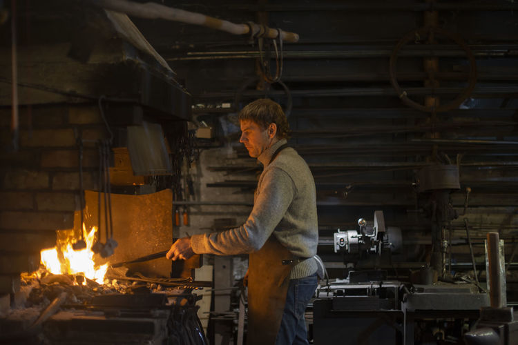Latvian blacksmith working with open fire in furnace. the blacksmith forging hot iron in workshop