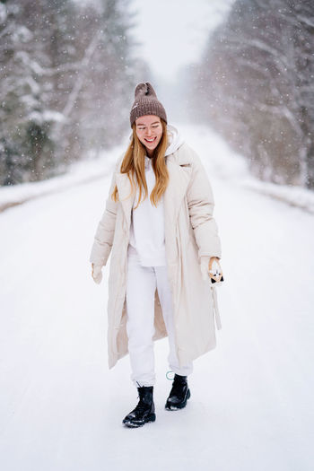 Portrait of young woman standing against snow