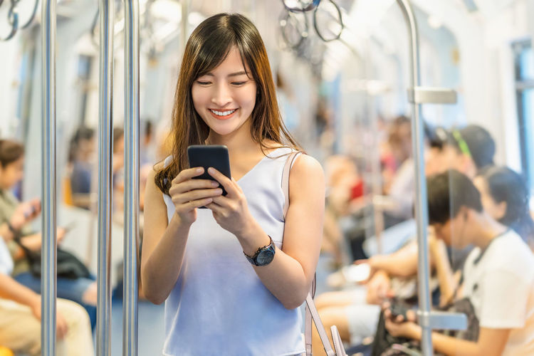 Young asian woman passenger using social network via smart mobile phone 