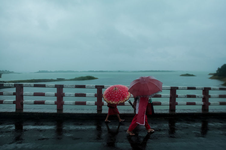 Woman standing on wet shore against sea during rainy season