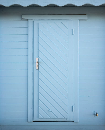 Matte pastel blue door and wall of horizontal wooden boarding.
