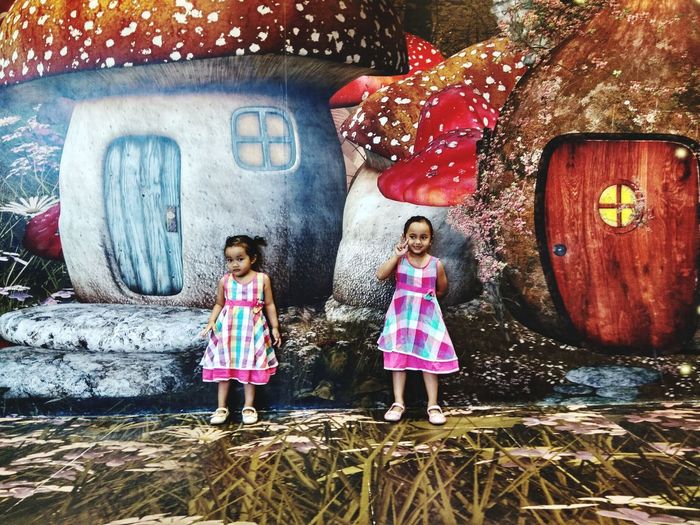 Cute sisters standing against graffiti wall