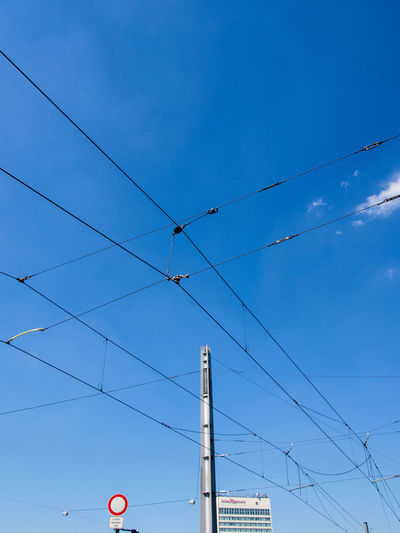 Low angle view of electricity cables against blue sky