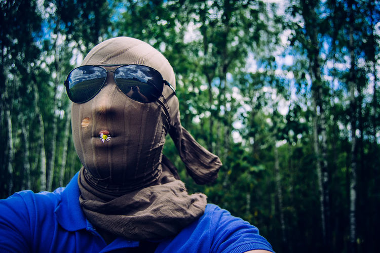 Man face covered with scarf in forest