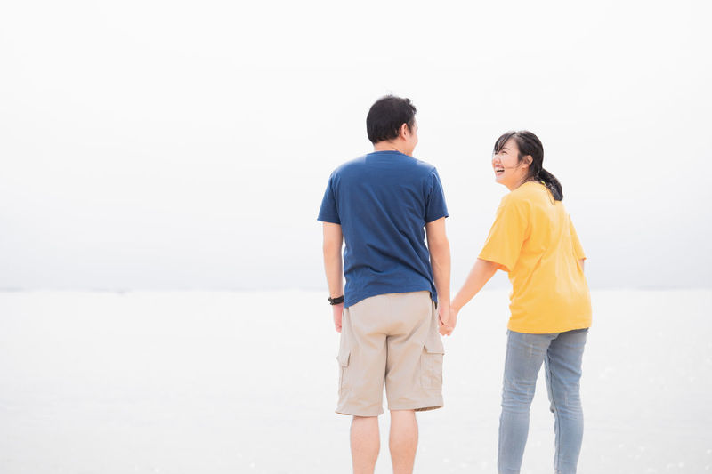 Rear view of couple standing against water
