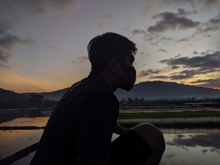 Side view of young man on rice field during sunrise