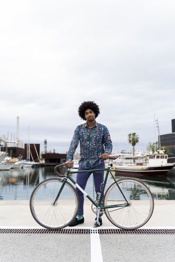 Portrait of stylish man with bicycle at the marina
