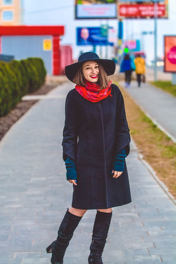 Portrait of smiling woman standing on footpath in city