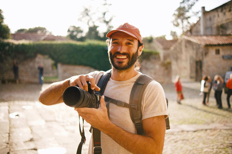 Portrait of a smiling young man holding camera