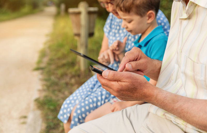 Family using mobile phone and digital tablet outdoors
