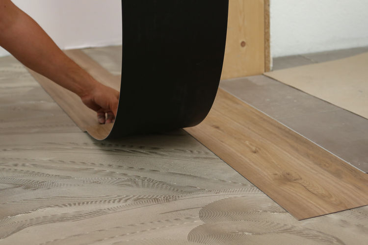 Cropped hand of carpenter installing laminate on floor