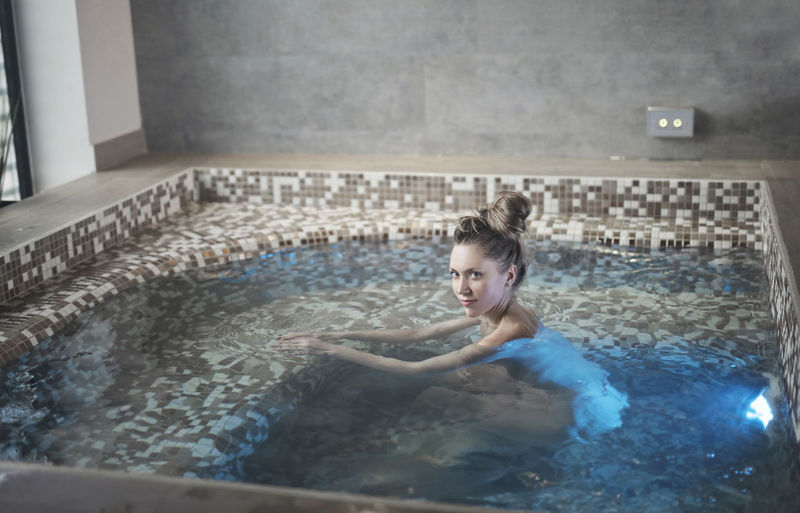Beautiful woman swims in a jacuzzi bathtub