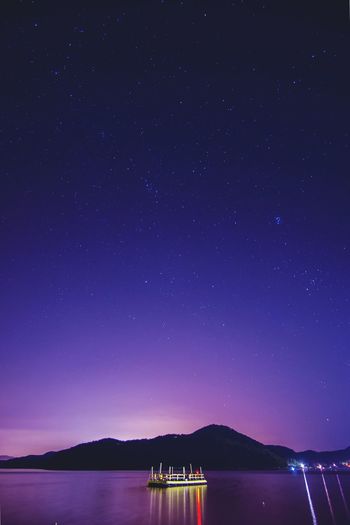 River by mountains against star field at night