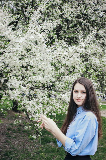 Portrait of a beautiful young woman standing by flowering plants