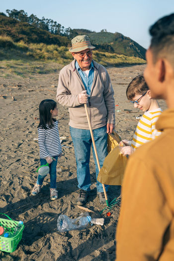 Grandfather smiling while standing with grandchildren at beach
