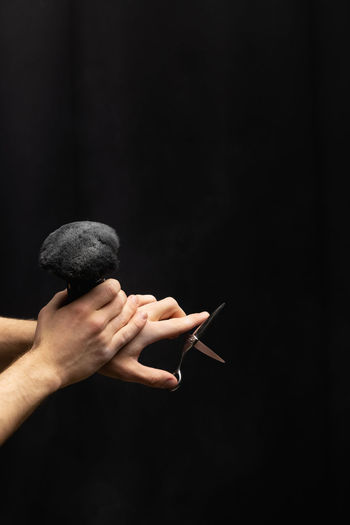 Cropped hand of woman gesturing against black background