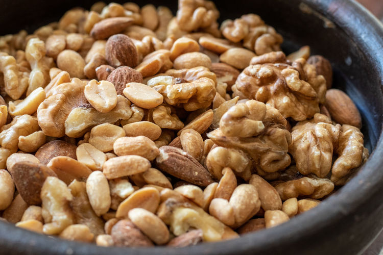 Mix of seeds, walnut, peanuts and almonds in a bowl on wooden table.