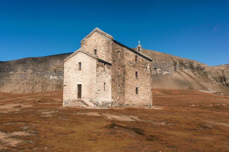 Old church on landscape against clear blue sky