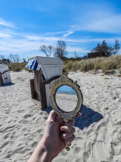 Cropped hand holding mirror at beach