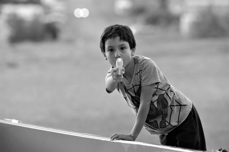 Portrait of boy aiming squirt gun while standing by railing