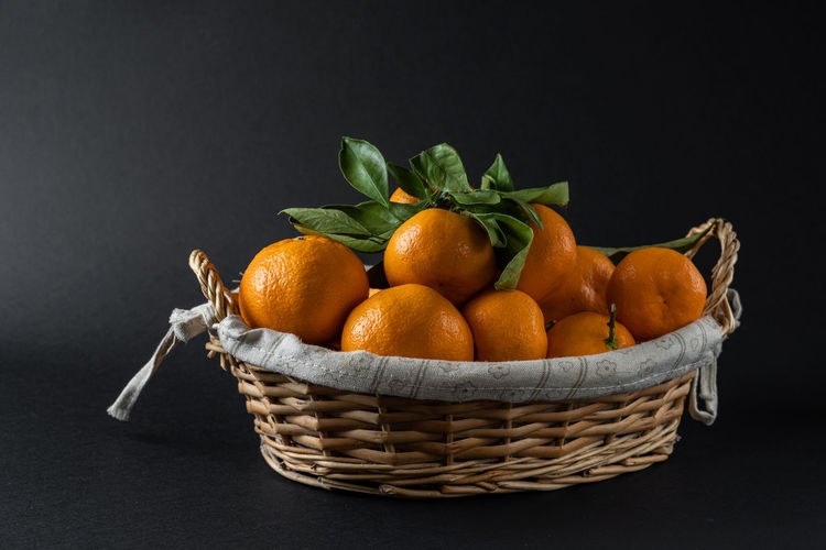 Close-up of fruits in wicker basket against black background