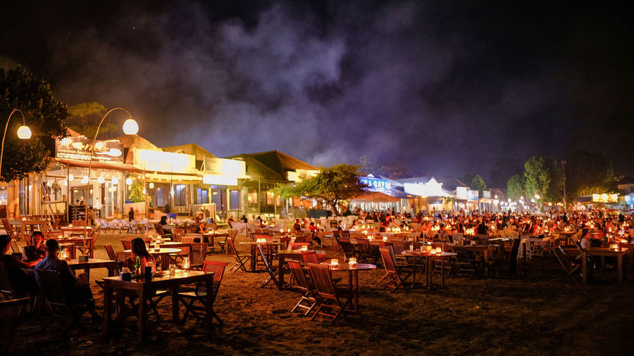 Panoramic view of people at restaurant against sky at night