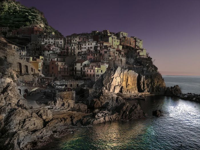 Town on cliff in sea against sky at twilight