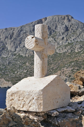 Close-up of cross on rock against sky