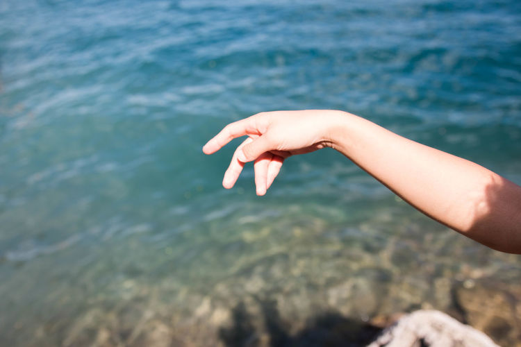 Close-up of person hand against lagoon