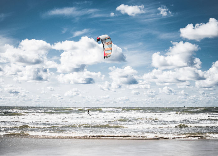 Scenic view of sea against sky with person kiteboarding