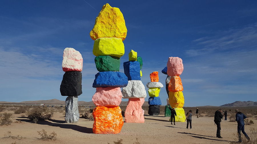 Tourists standing by colorful rock stacks against sky