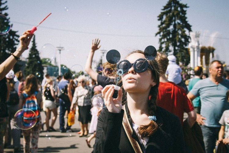 Teenage girl blowing bubbles against crowd