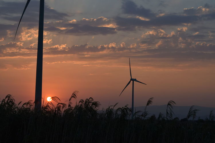 Wind turbine against sky during sunset