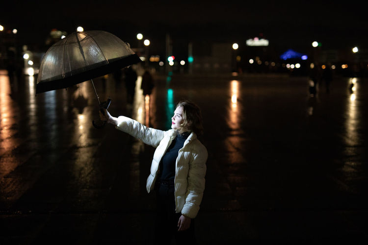Young woman holding umbrella outdoors during rainy season